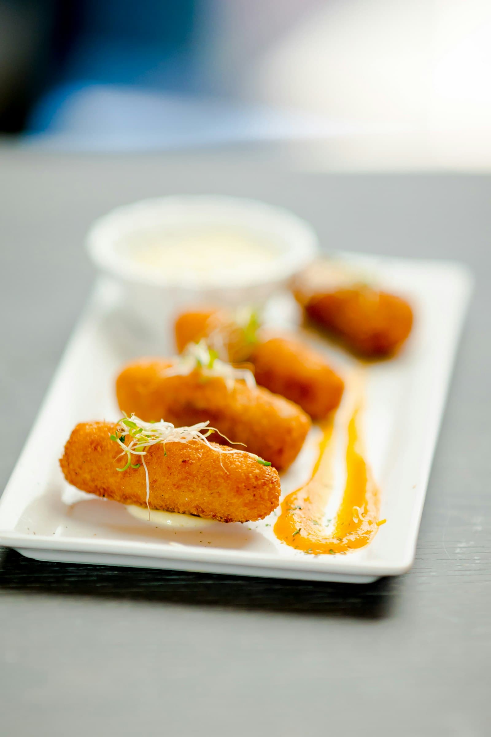 Fried croquettes on a white plate with a dipping sauce