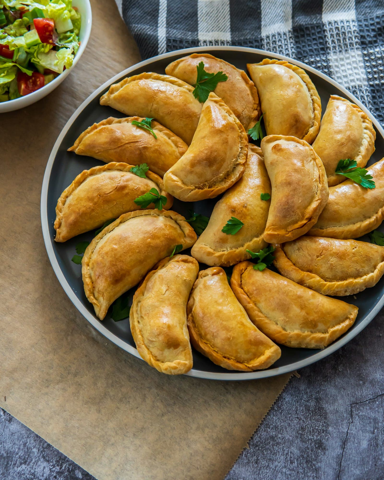A plate of baked empanadas scattered with parsley