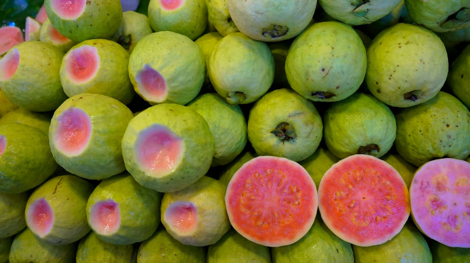 Whole and halved guavas, pink inside
