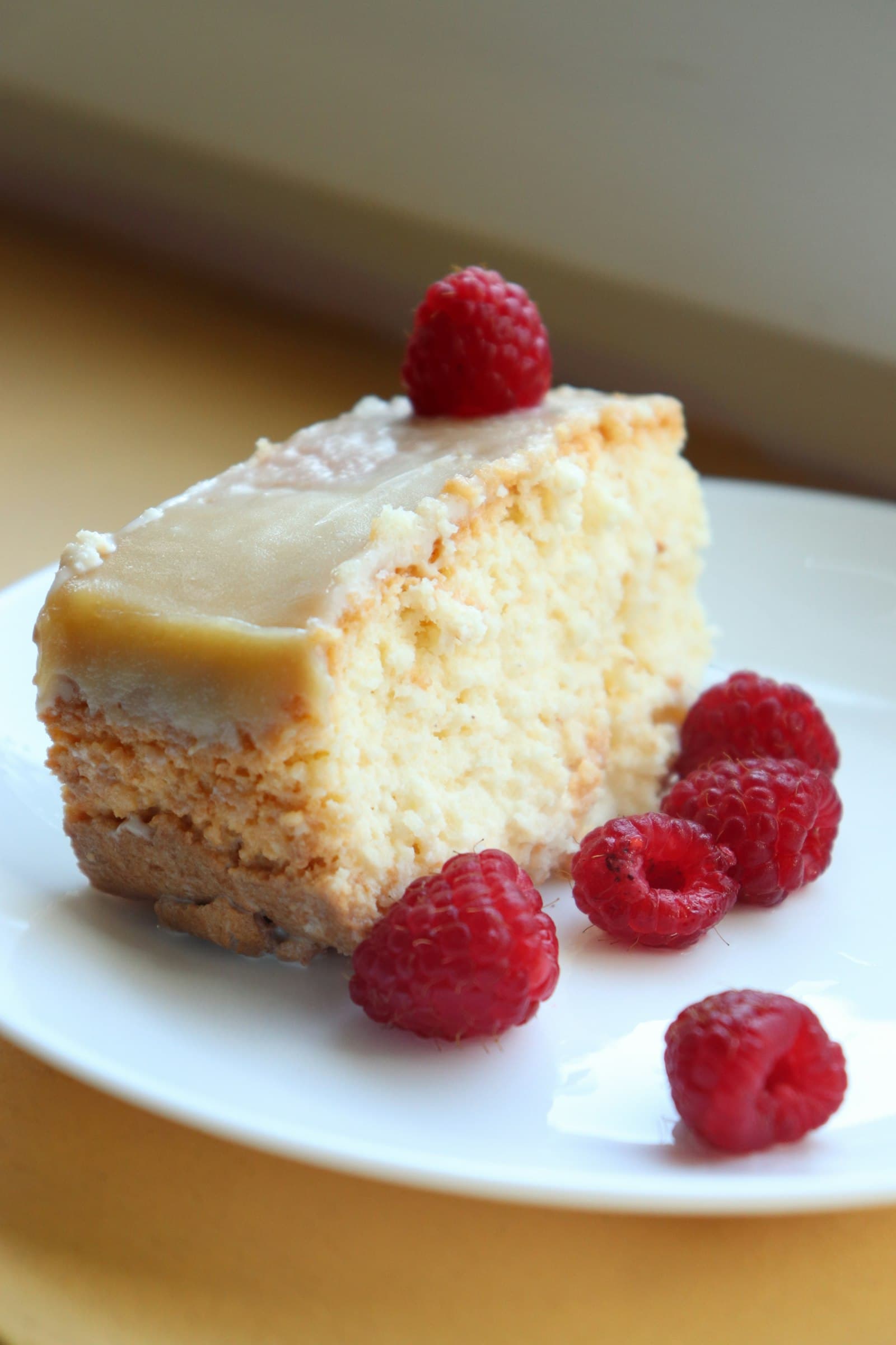 A slice of sponge cake with raspberries on a white plate
