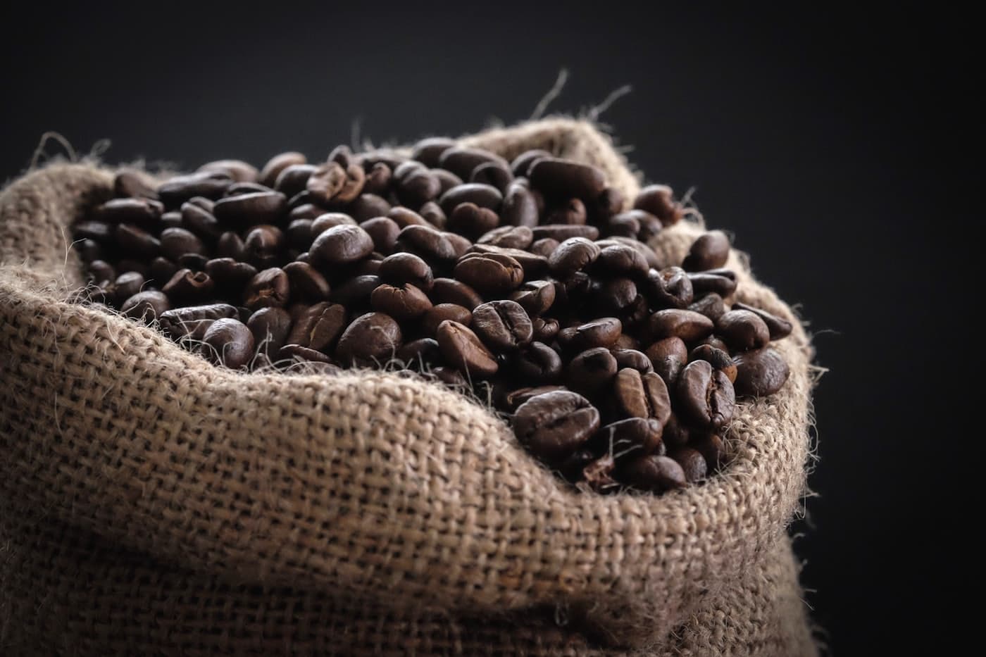 Open burlap sack heaped with freshly roasted coffee beans