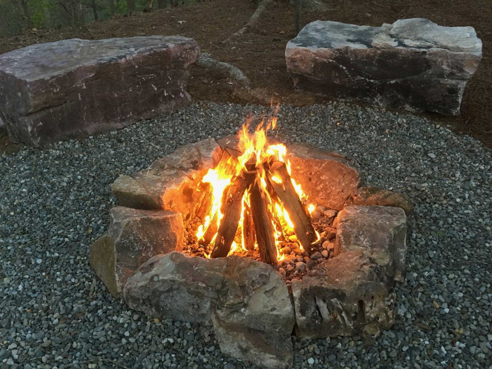 A stone fire pit with a lit fire