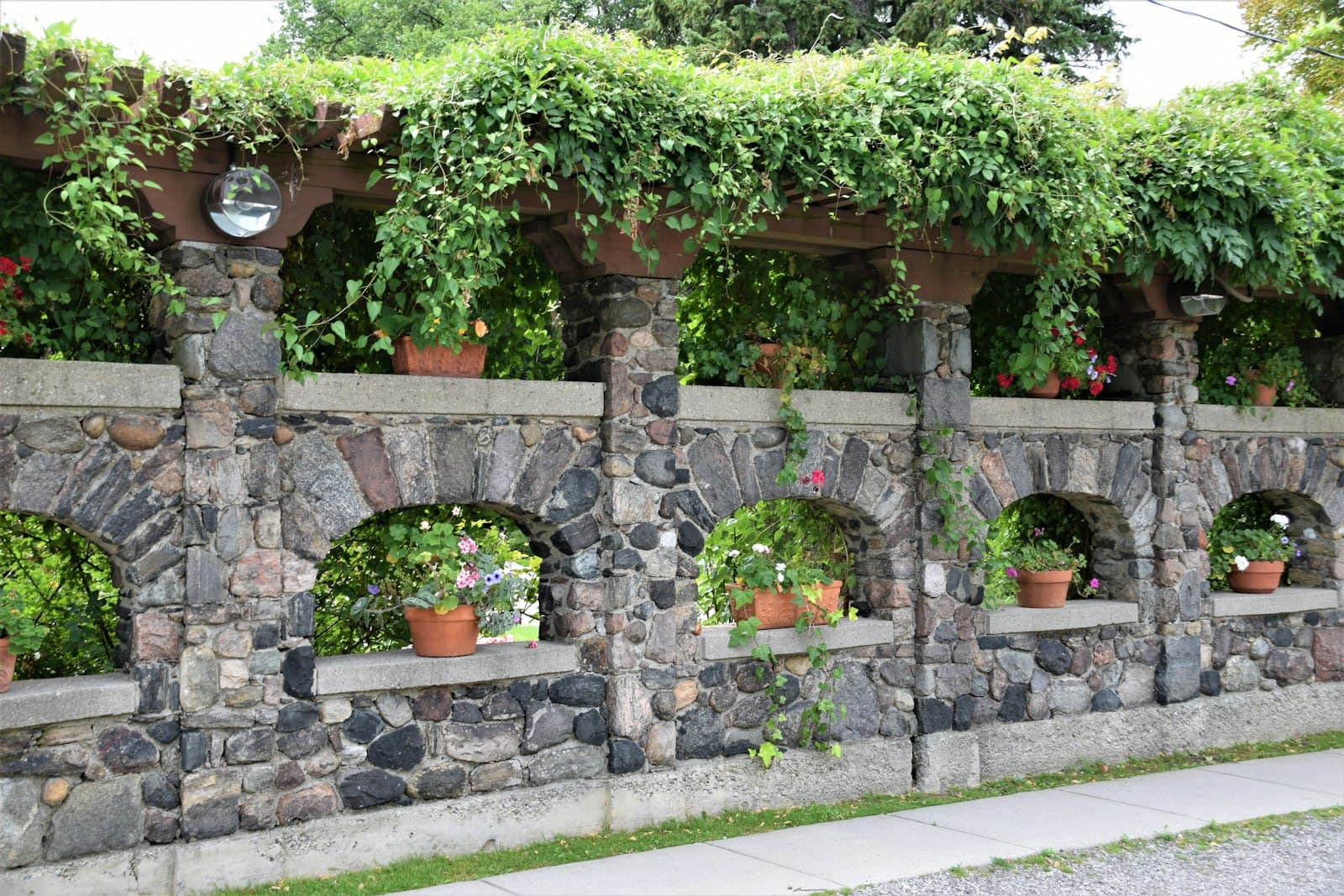 A stone wall planted with potted greenery