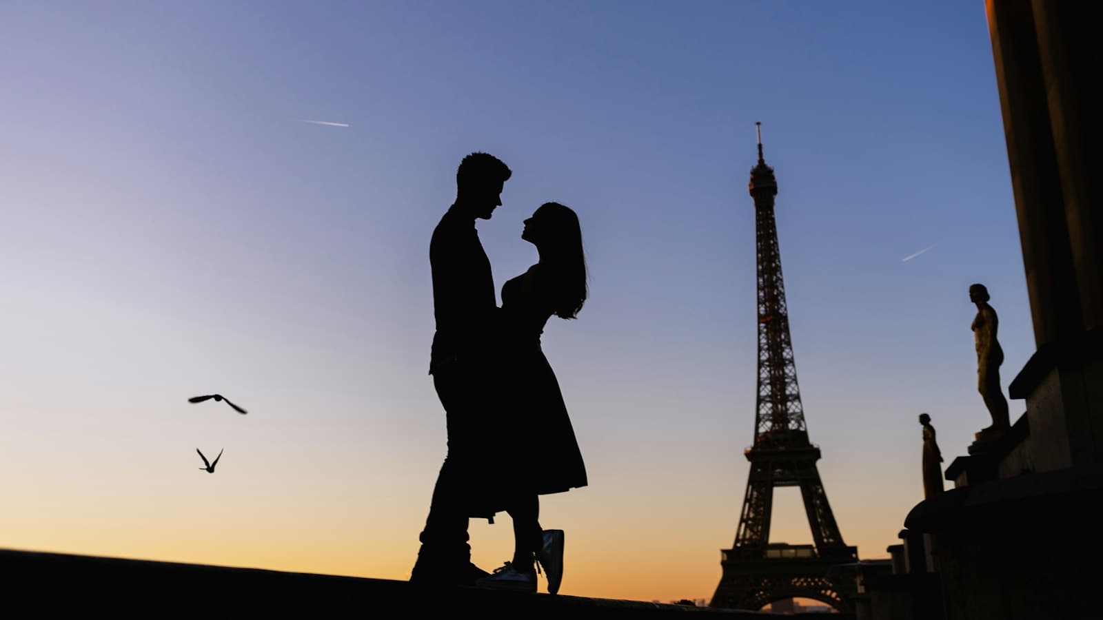 Silhouette of a couple facing each other at first light, the Eiffel Tower beside them
