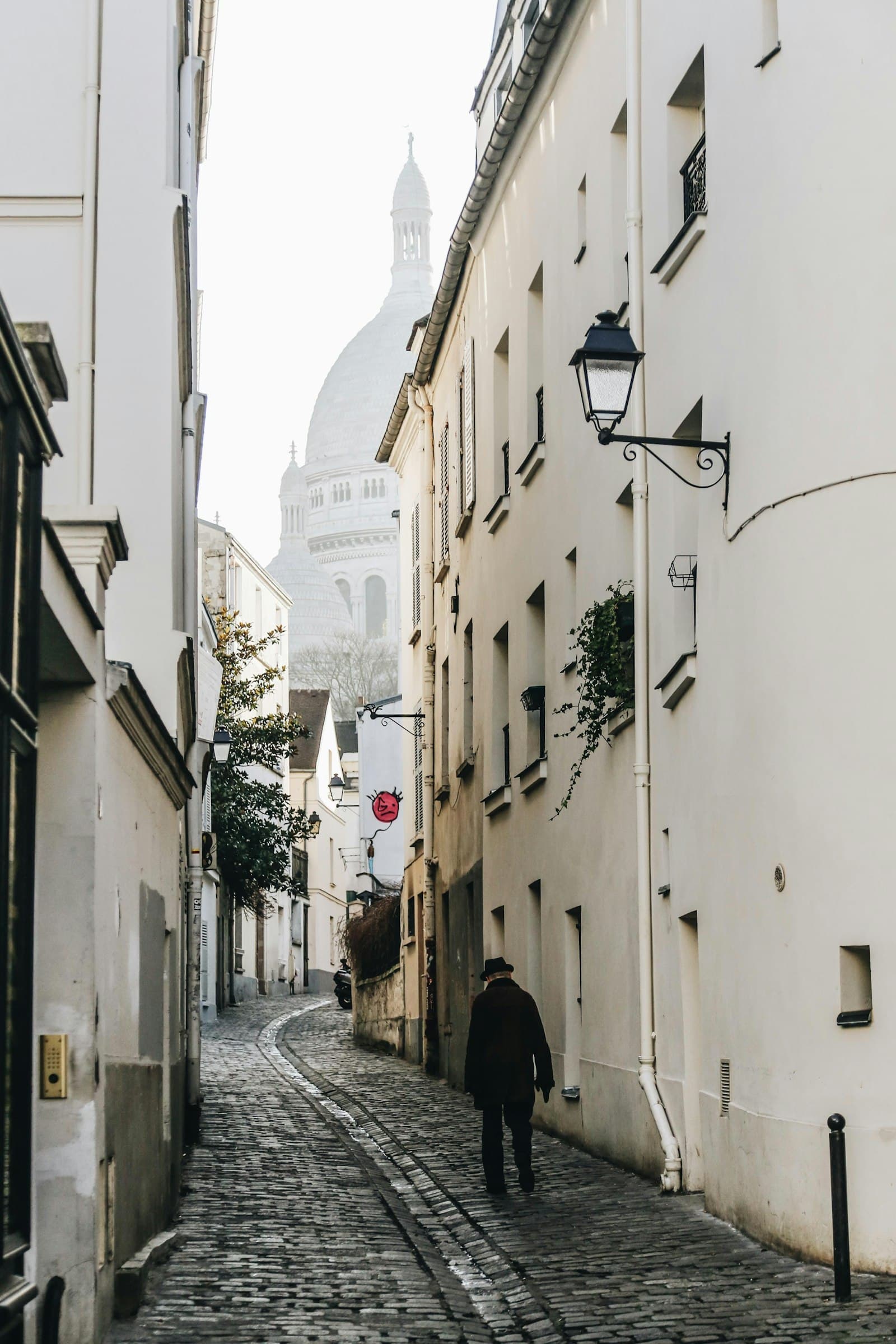 A cobbled lane in Montmartre with the dome of Sacré-Cœur at the end