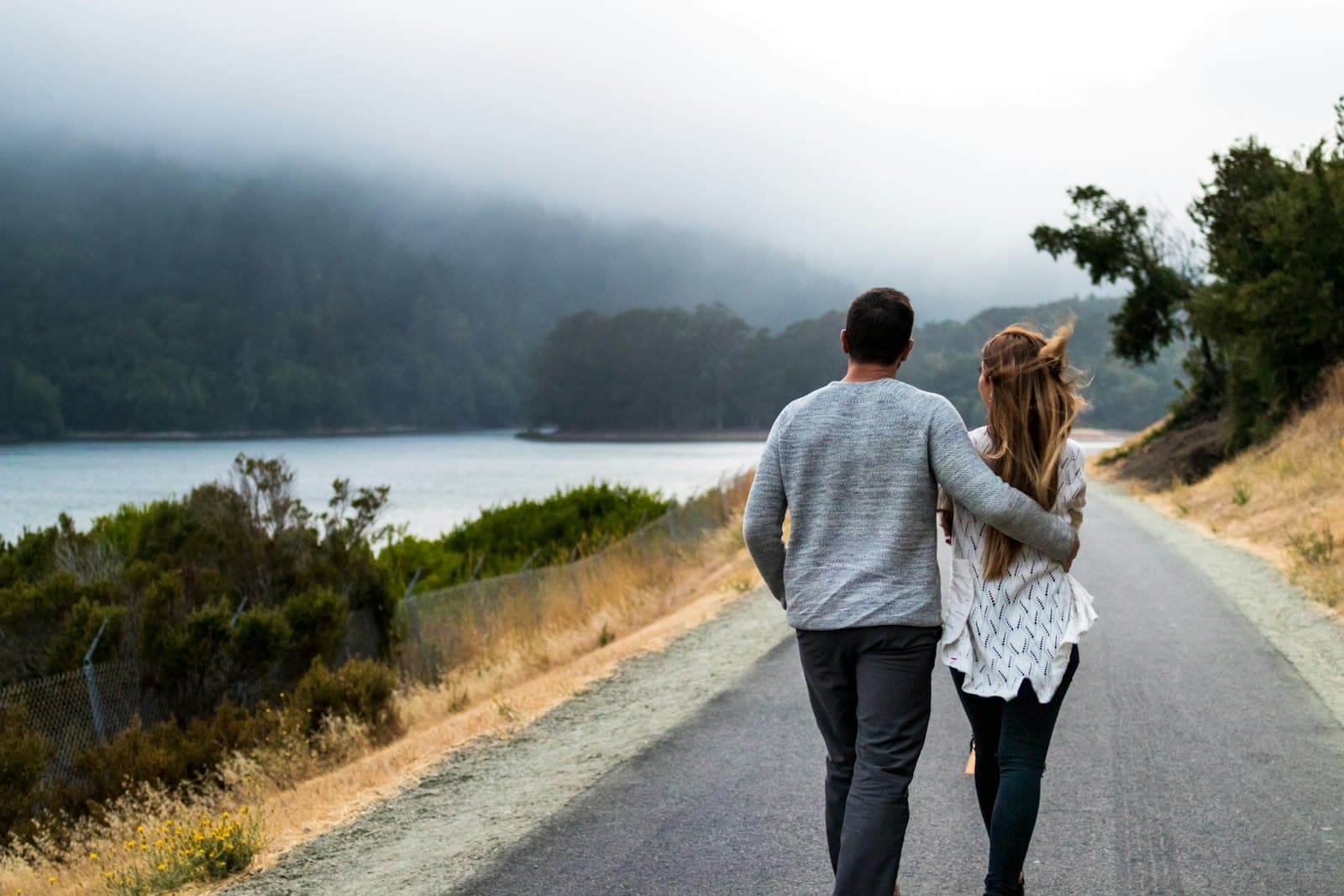 Two people walking away down a coastal road