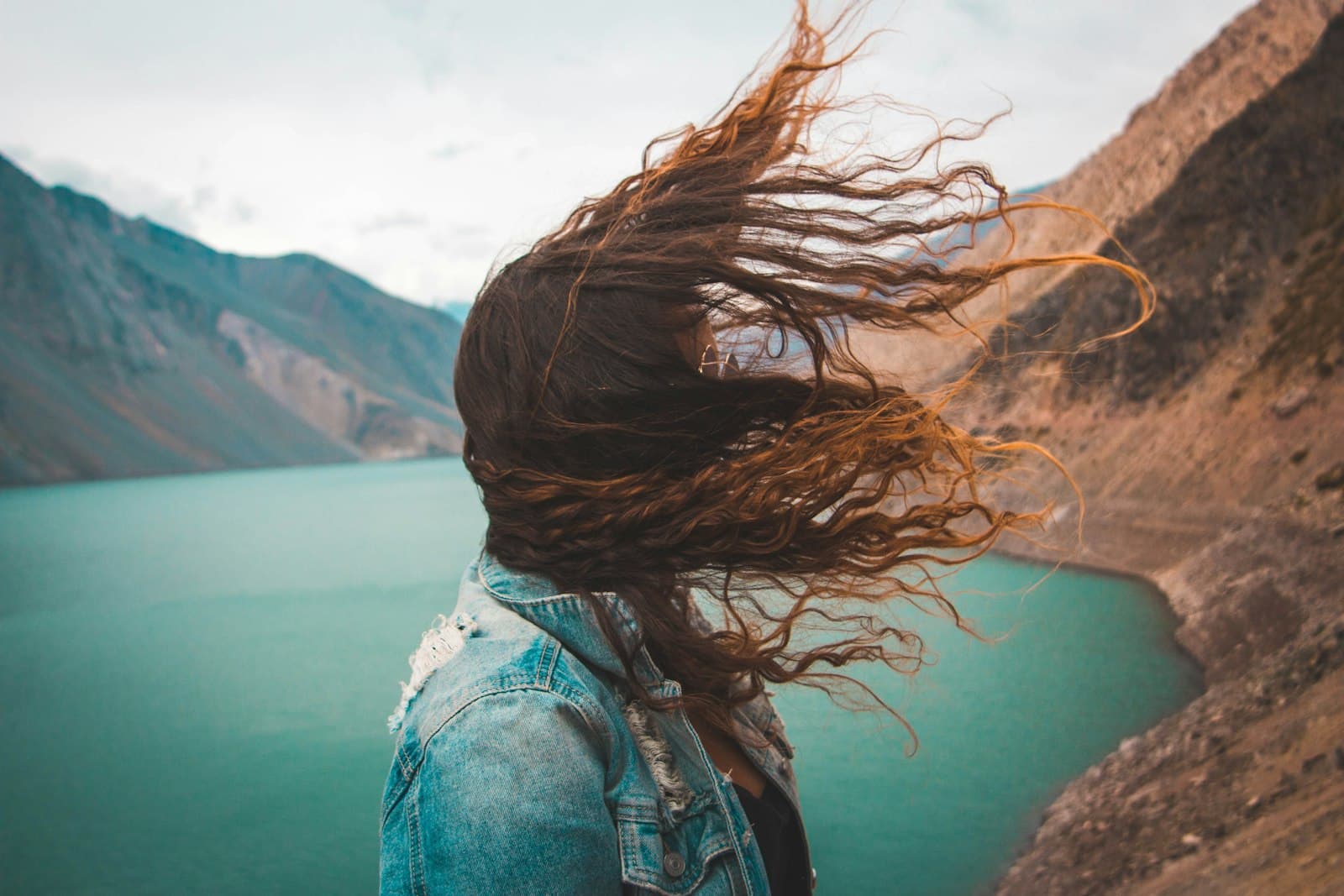 A figure at the shore with hair caught in the wind
