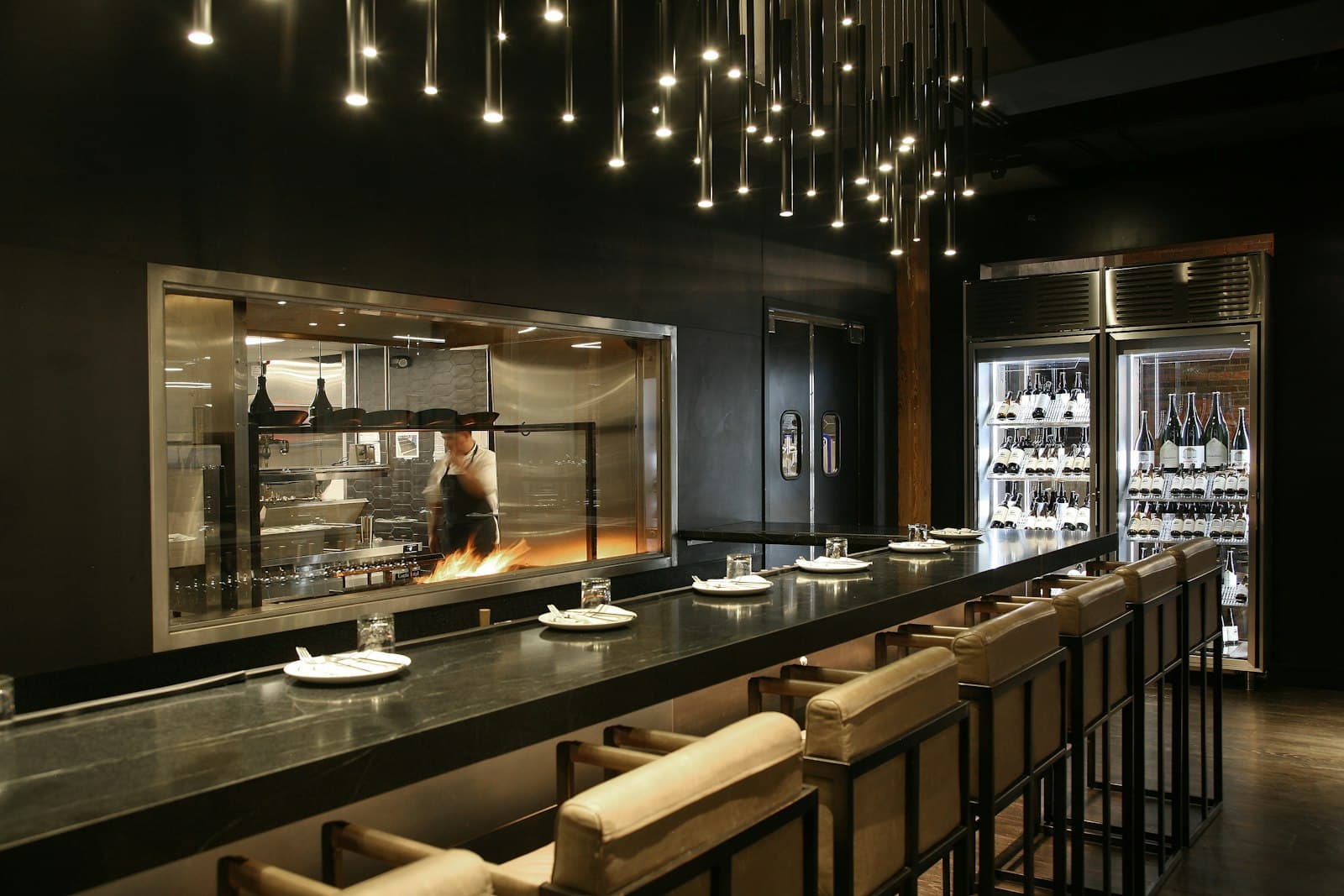 A long counter with stools and hanging lights