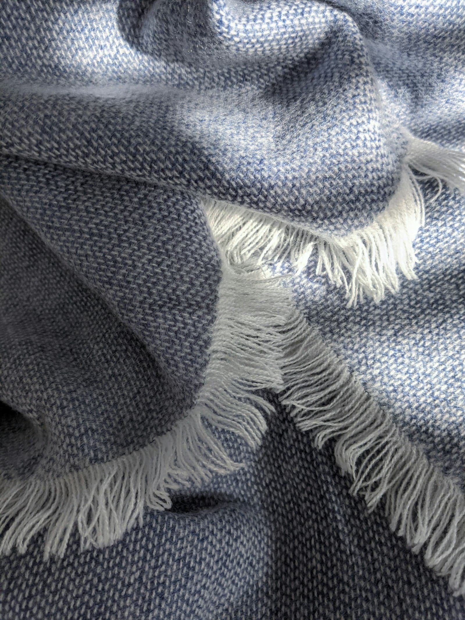 A folded wool blanket with fringed edge