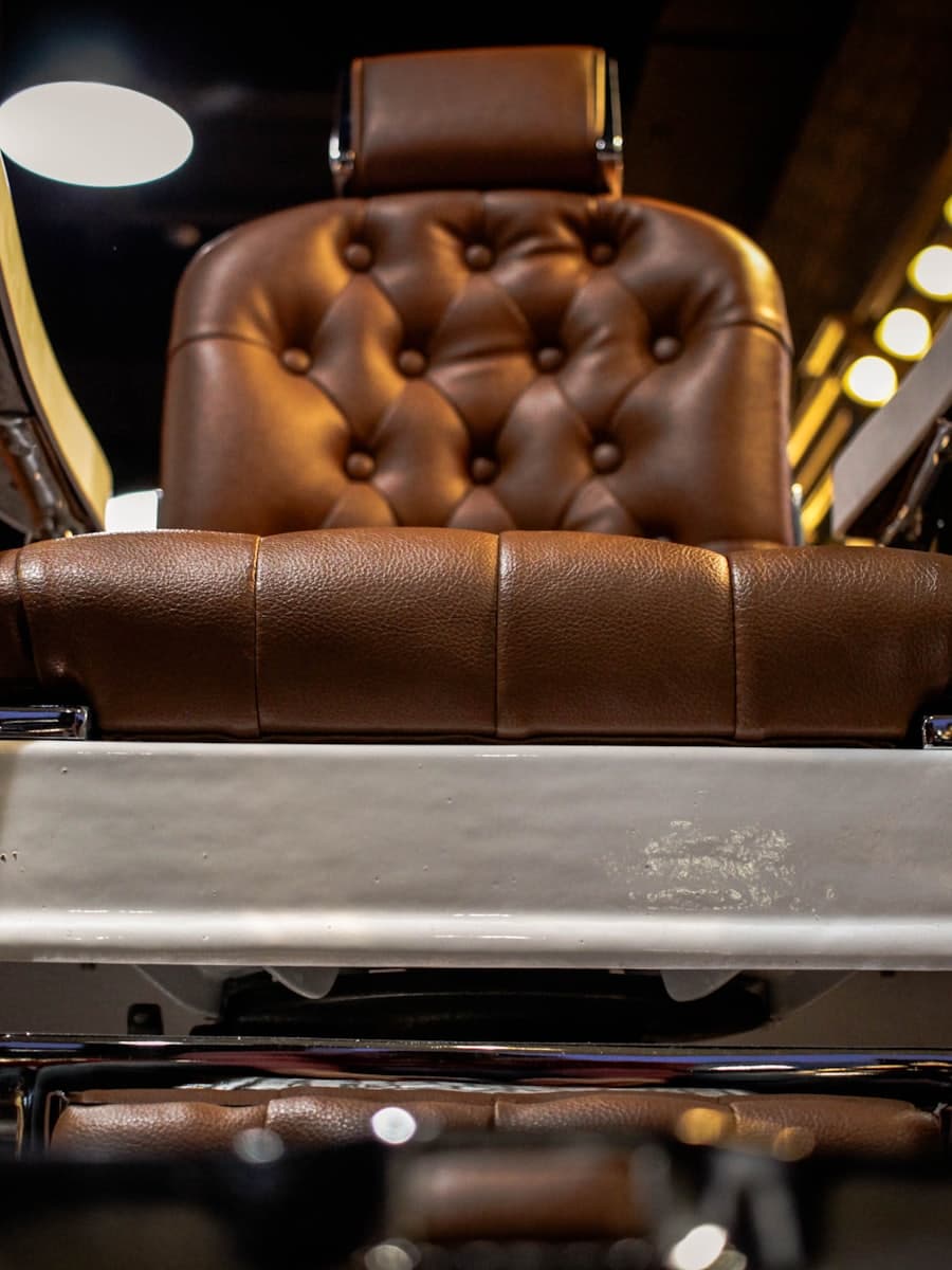 Tufted brown leather barber chair under warm shop lights