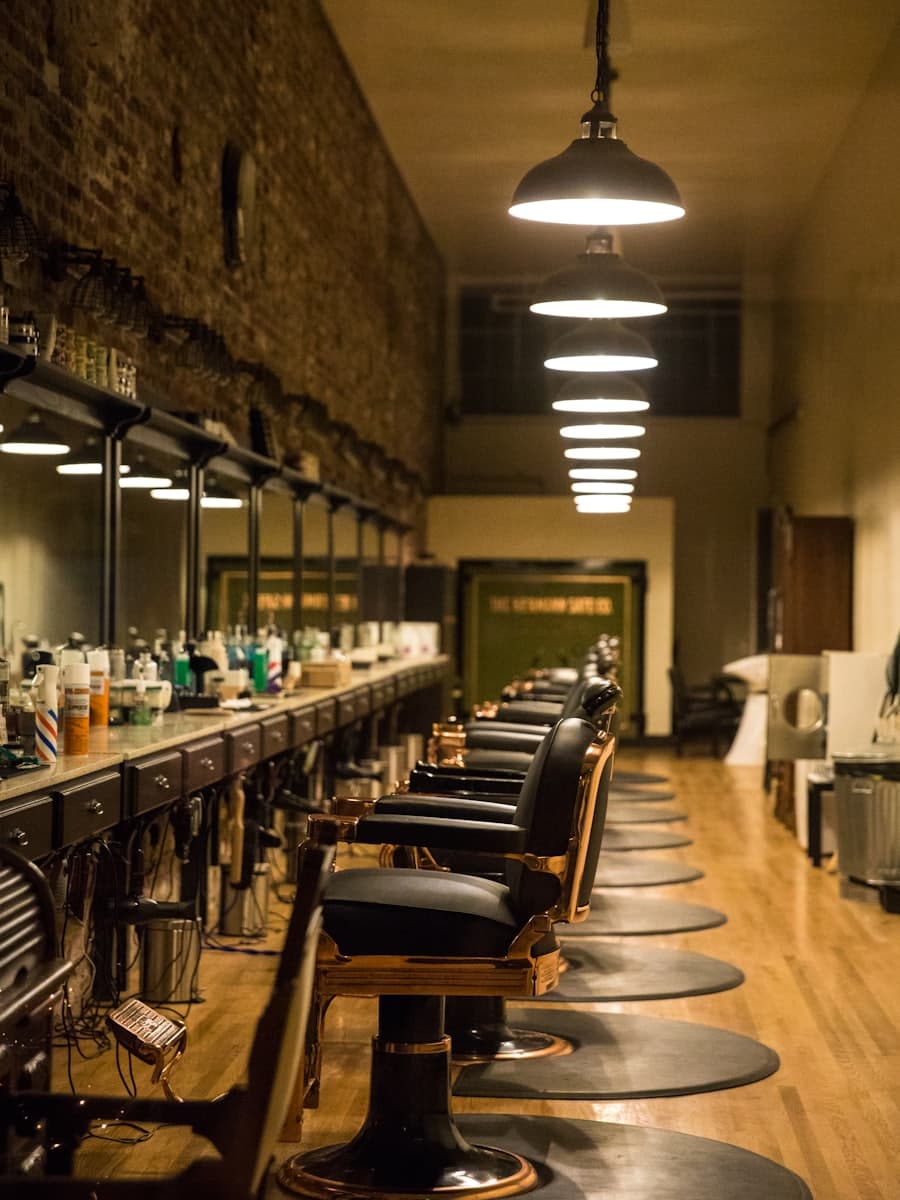 Row of vintage barber chairs along a brick wall