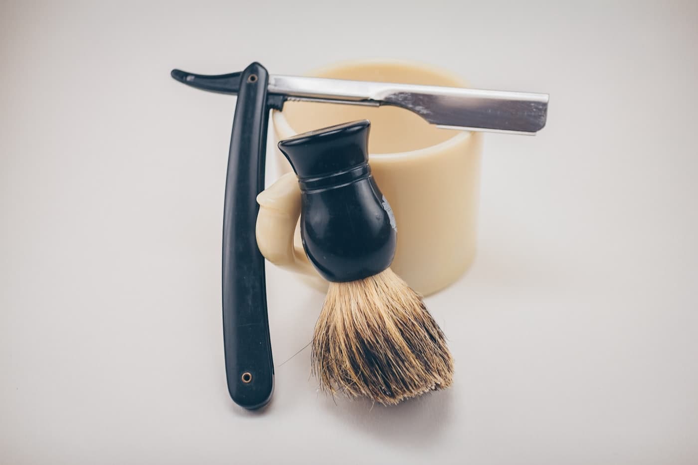 Shave brush, lather mug and straight razor on a counter