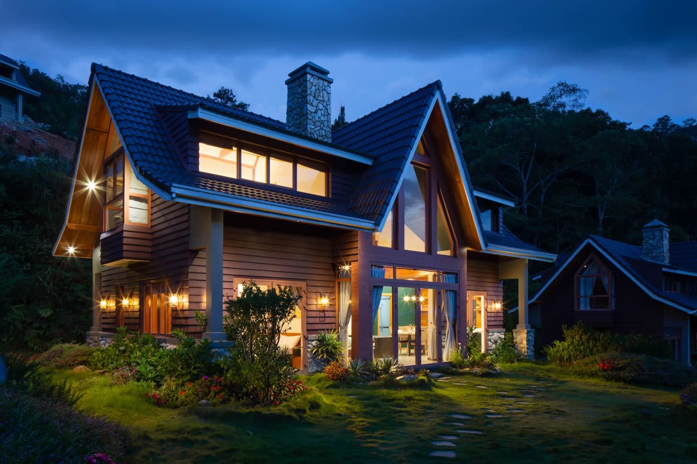 Timber home with lit windows at dusk under a deep blue evening sky