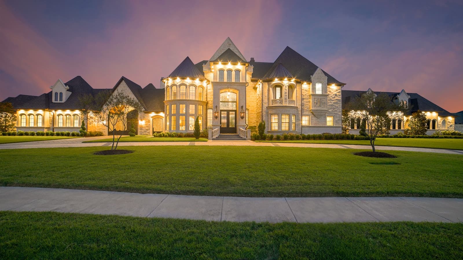 Stone estate home with warm lit windows at dusk