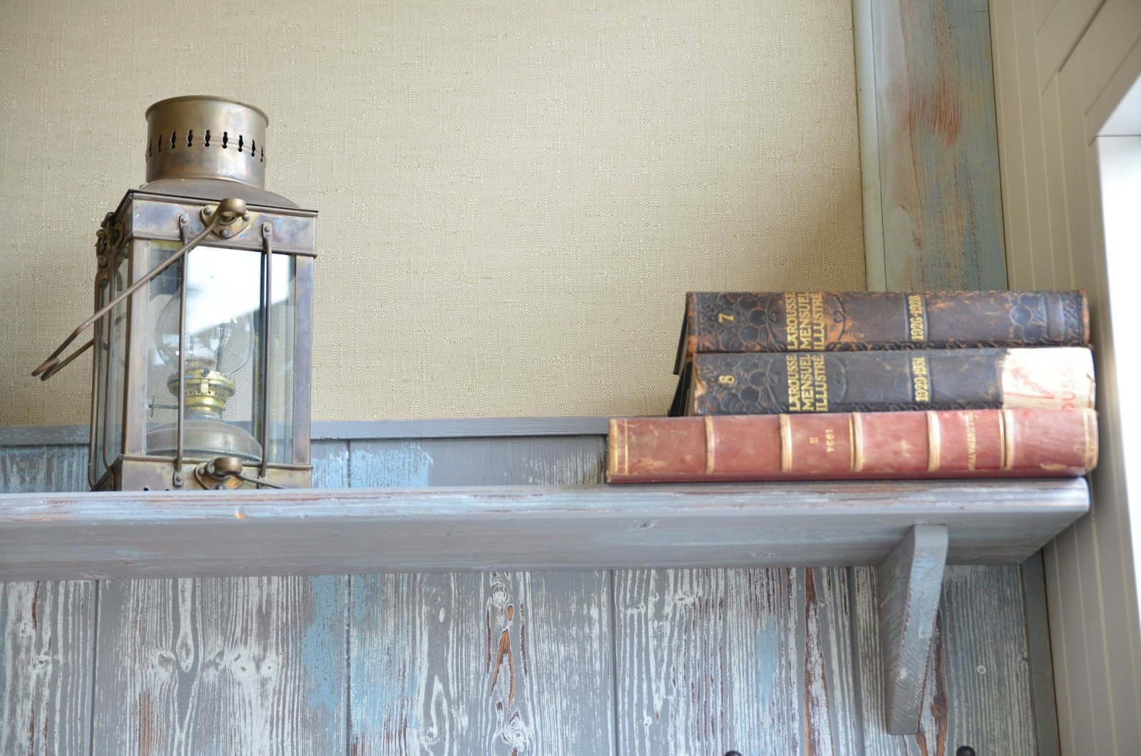 Antique lantern beside old bound books on a shelf
