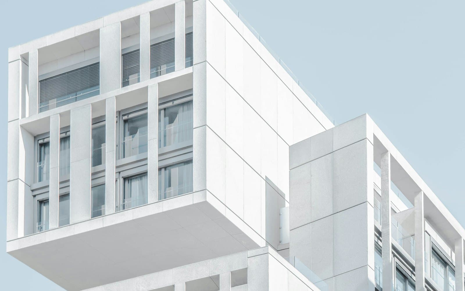 White modular residential facade with deep balconies against a pale sky