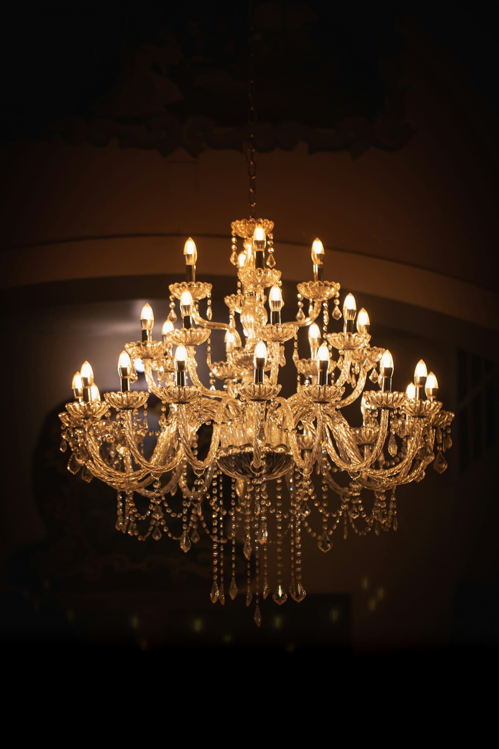Crystal chandelier glowing warm gold in a dark room