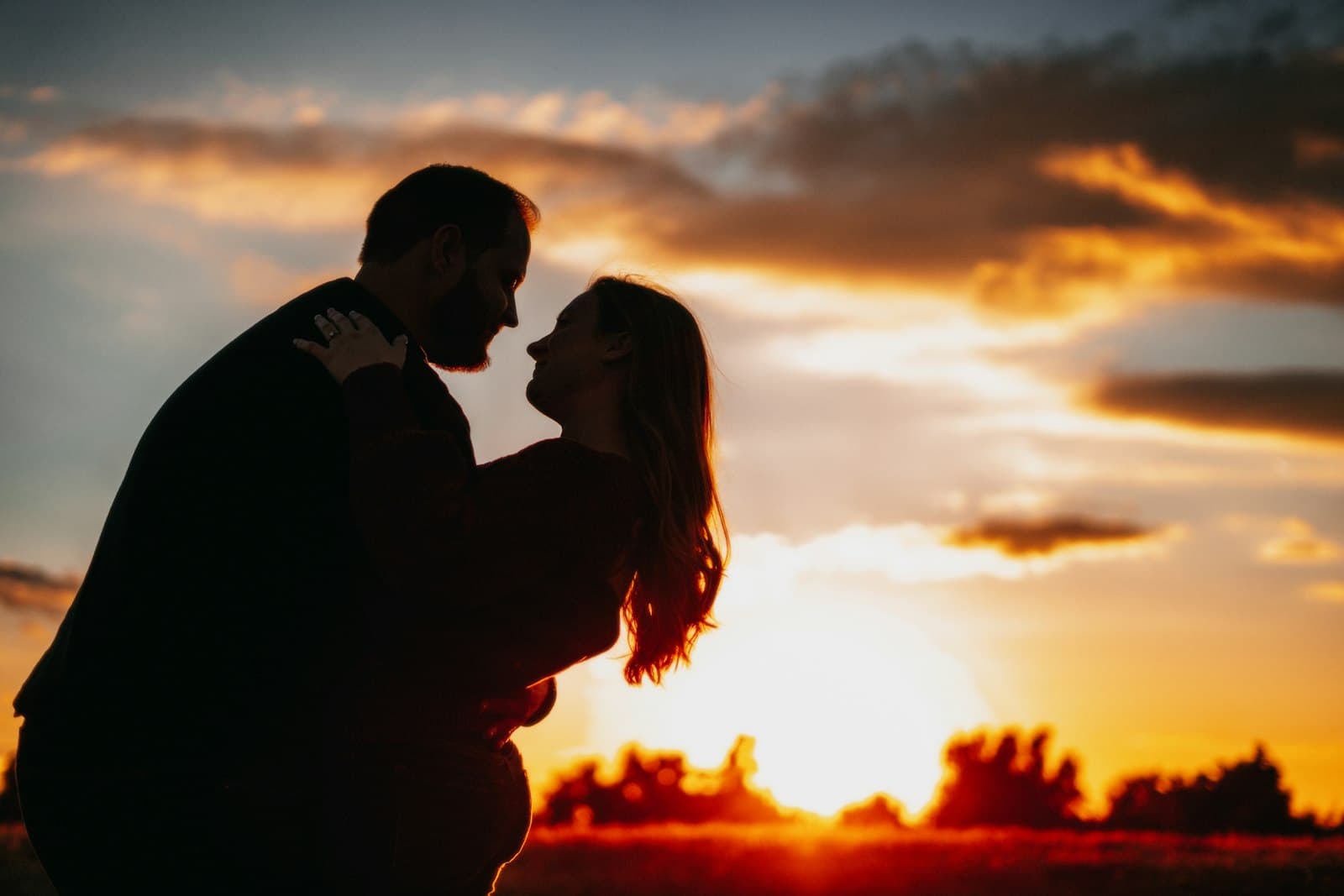 Two people silhouetted against a sunset sky
