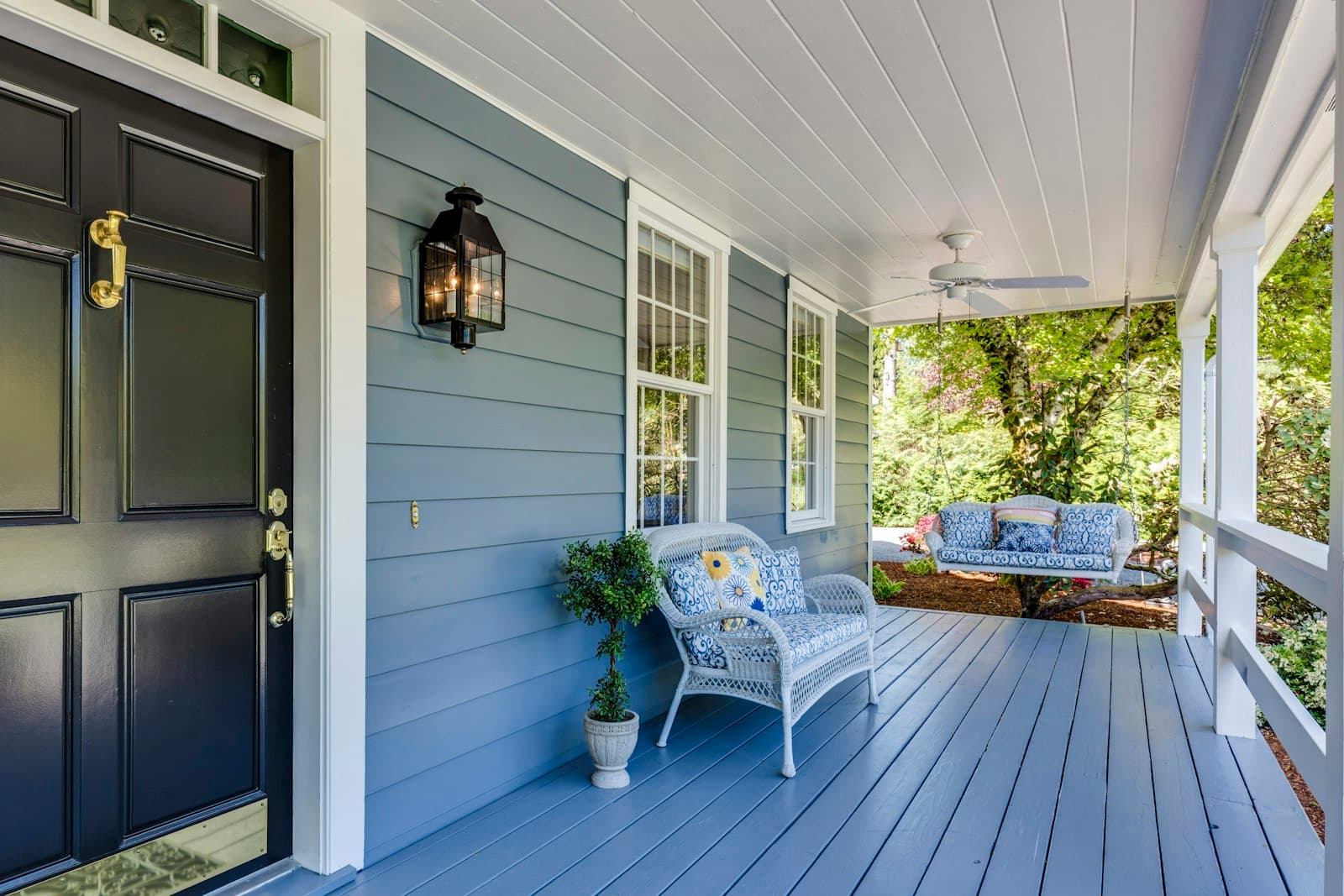 A covered front porch with a painted deck and a swing