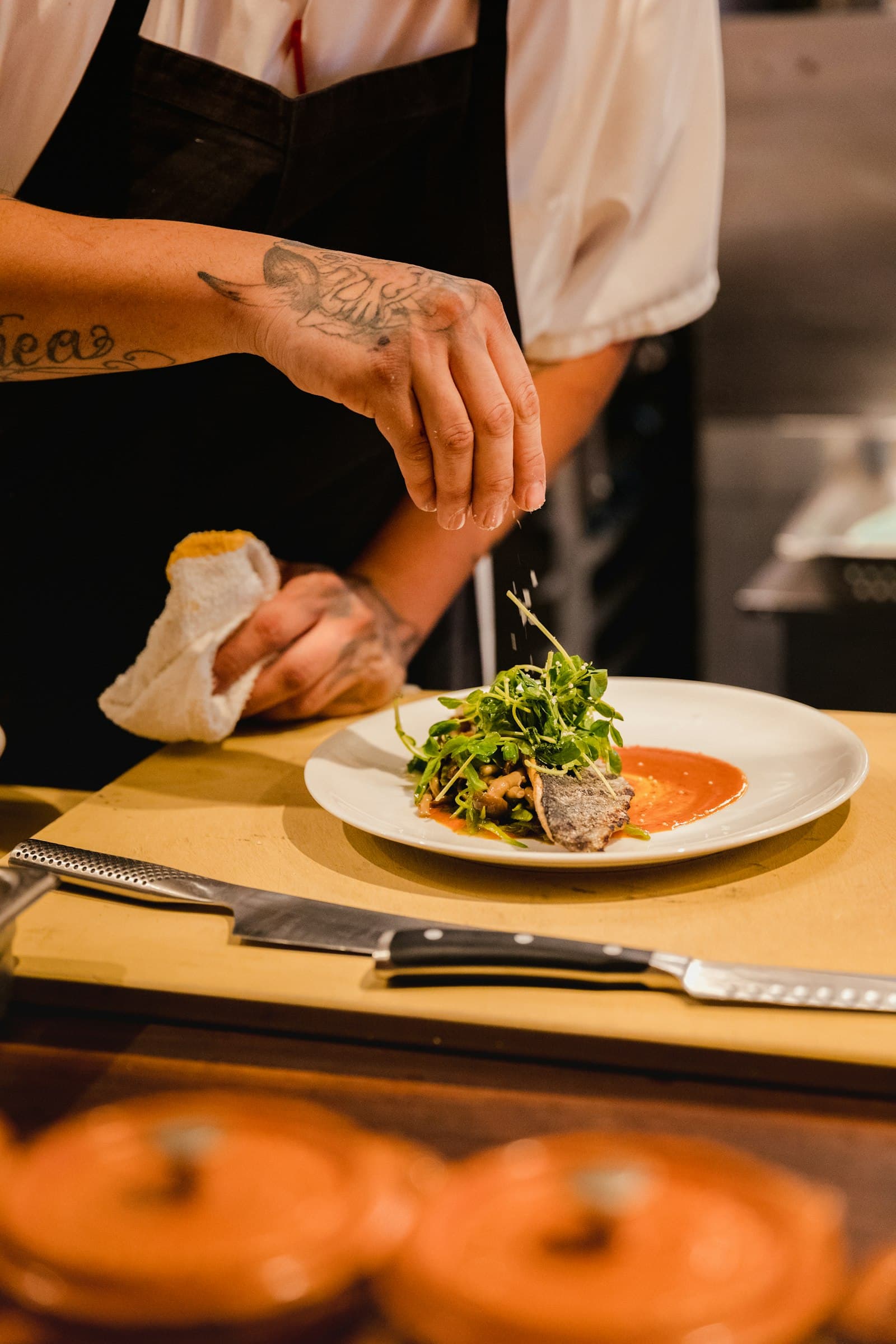 A cook finishing a plate at the pass