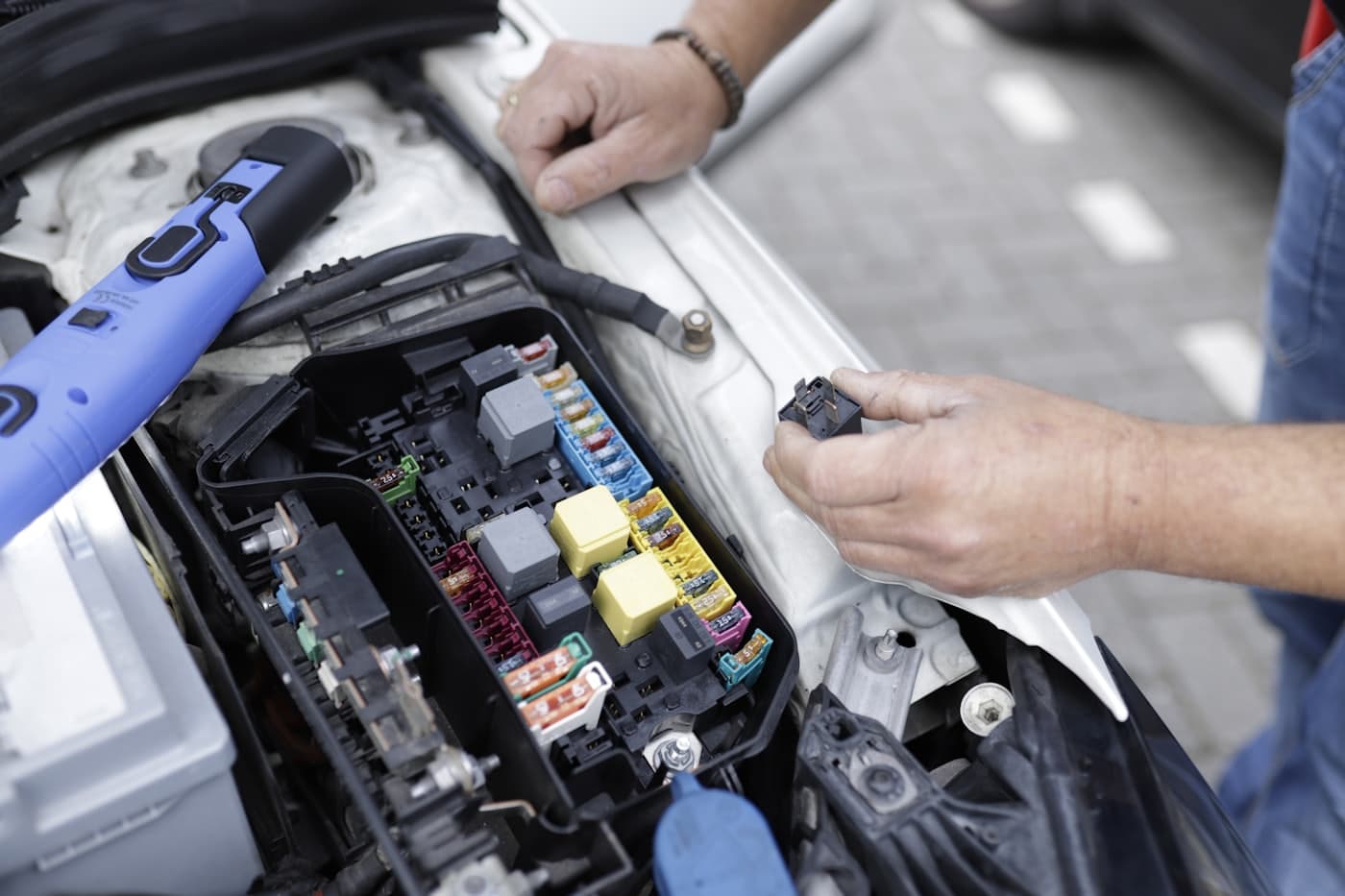 Technician testing relays in an under-hood fuse box